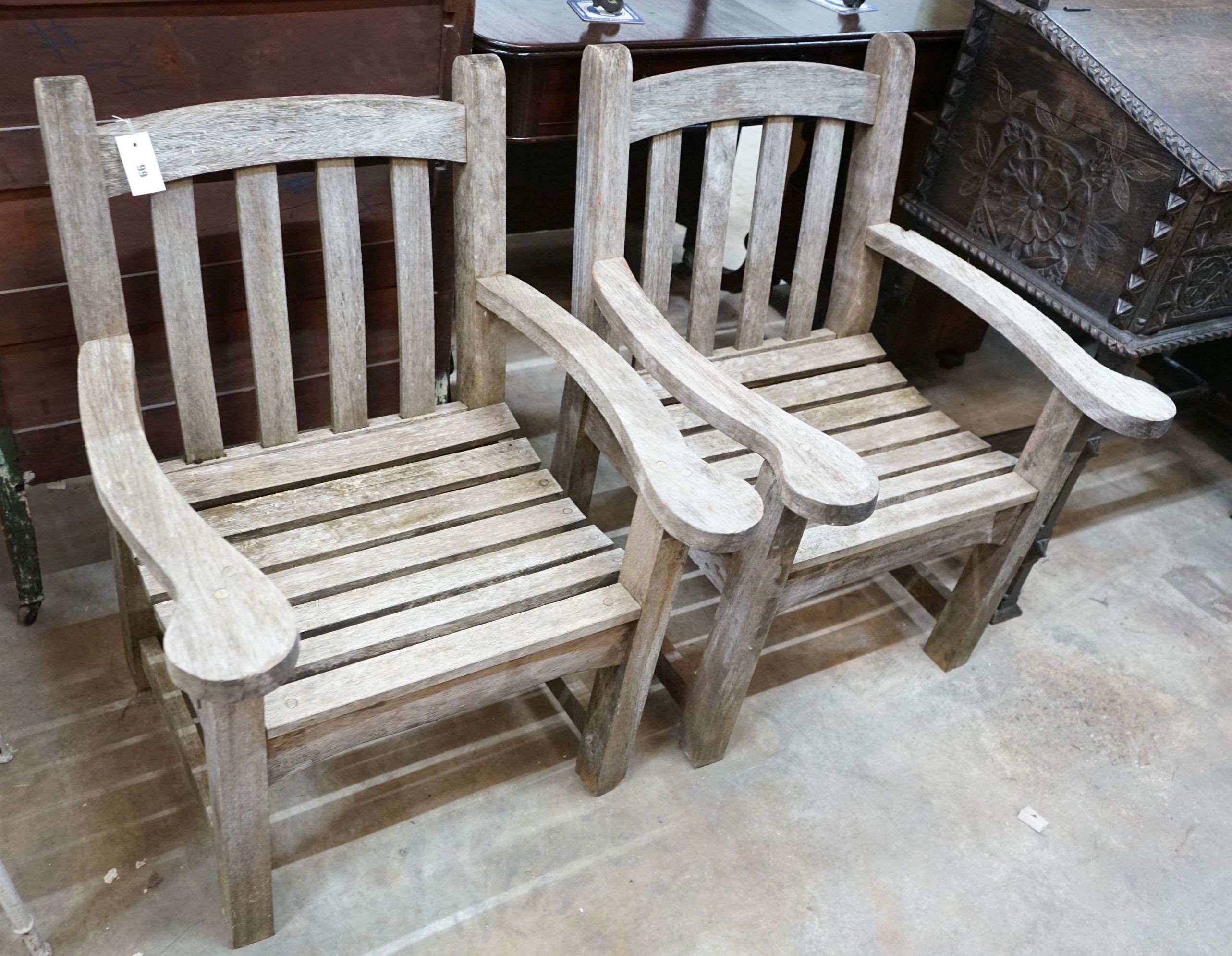 A pair of weathered teak garden armchairs, width 65cm, depth 58cm, height 87cm